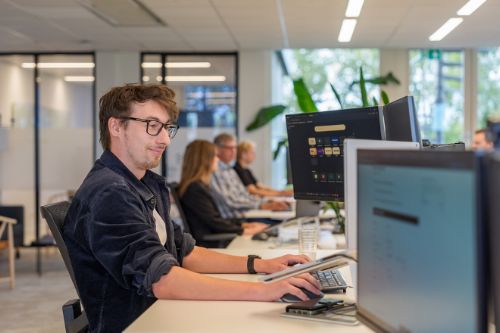 Ontwikkelaar werkt aan systeemkoppeling voor PIM-oplossing in open kantoor